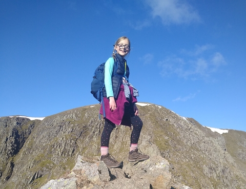 A young girl in hiking gear standing on a rock