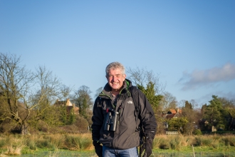 Tony stands in a wetland with his dogs