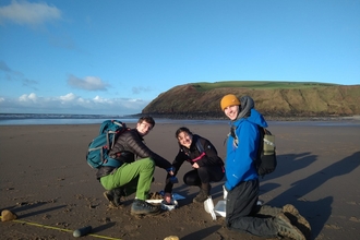 Image of three people carrying out survey on beach