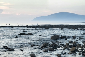 Image of Earnse Bay with swimmers and Black Combe in background