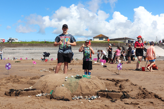 Image of families on beach at St Bees with sand sculpture of turtle