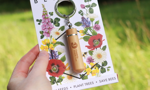 A bamboo keyring engraved with the Cumbria Wildlife Trust logo in floral packaging