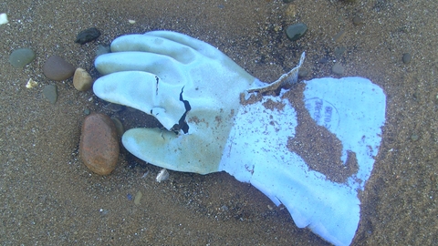 Blue industrial rubber glove washed in on the tide