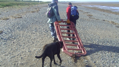 Plastic crash barrier beibg dragged from the beach