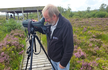 Image of volunteer Matthew Cookson looking down telescope at Foulshaw Moss Nature Reserve