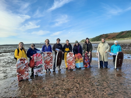 Image of nine people on beach with body boards about to collect seagrass seed