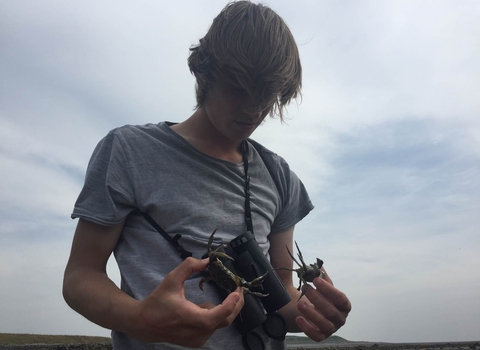 image of student wearing binoculars holding crabs